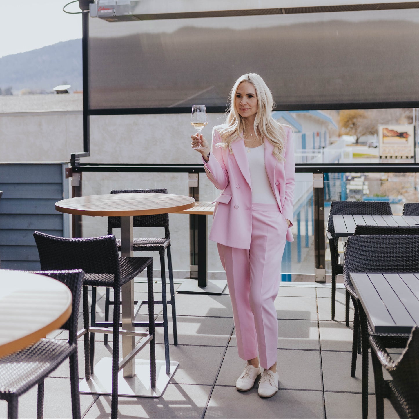 Marina Billinghurst in a pink suit holding a glass of glimmer in the patio at Saltys in Penticton