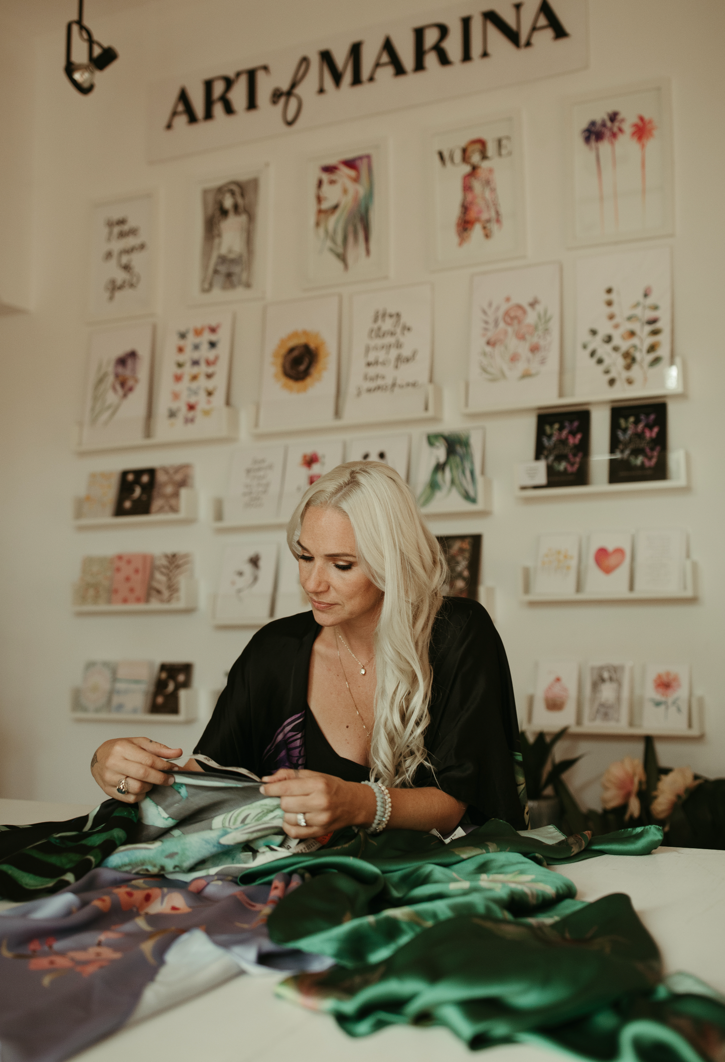 Marina Billinghurst working on a project with fabric and art supplies in a room with 'Art of Marina' displayed.